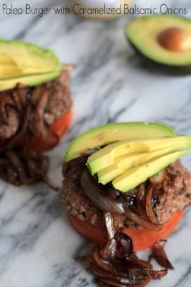 Stacked paleo burger with caramelized onions, tomato, and avocado slices