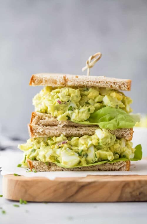 a stacked sandwich with bread, avocado egg salad and lettuce