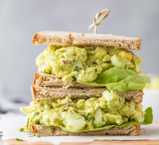 a stacked sandwich with bread, avocado egg salad and lettuce