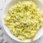 a bowl of egg salad with red onion and chive garnish