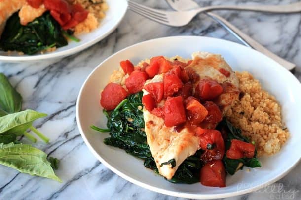 Balsamic Chicken with Baby Spinach and diced tomatoes on a plate with couscous