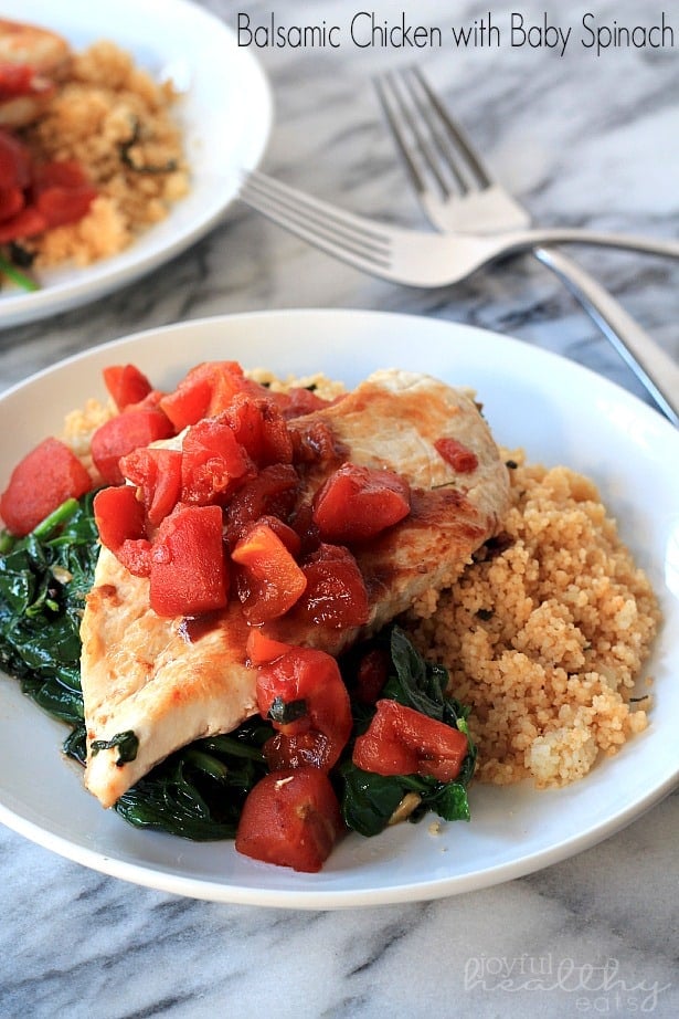 Balsamic Chicken with Baby Spinach and diced tomatoes on a plate with couscous