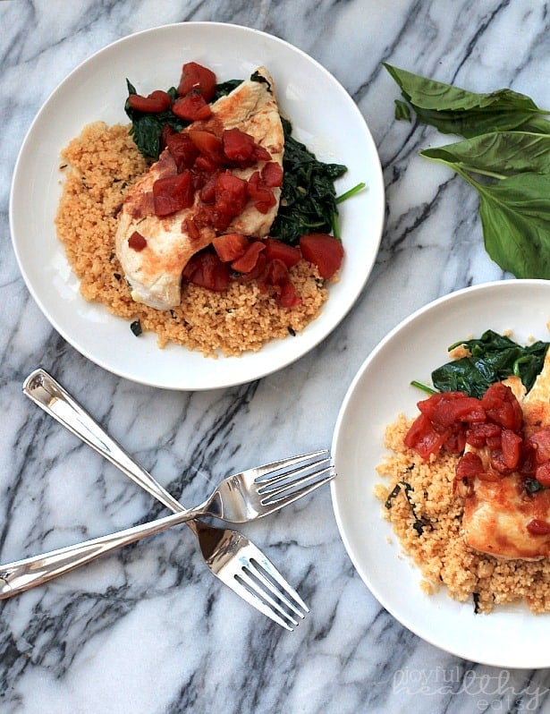 Balsamic Chicken with Baby Spinach and diced tomatoes on a plate with couscous