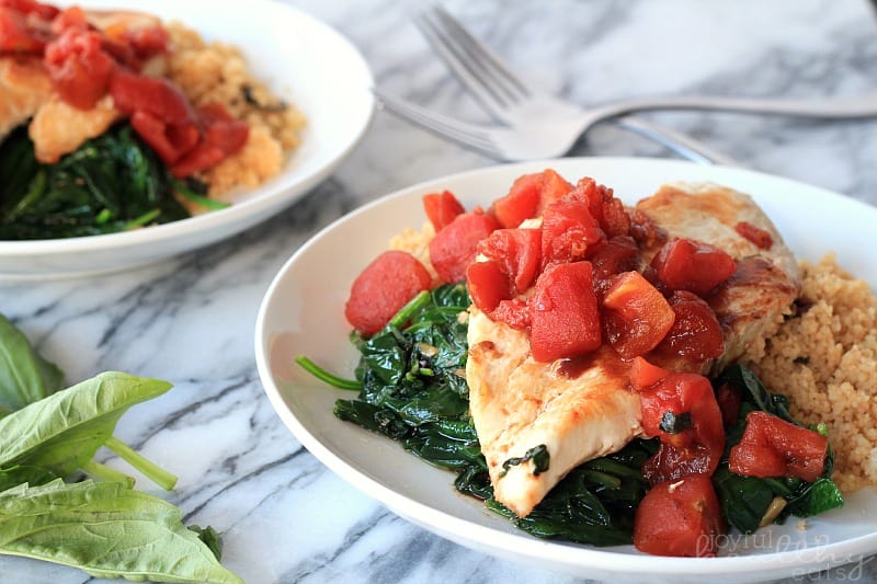 Balsamic Chicken with Baby Spinach and diced tomatoes on a plate with couscous