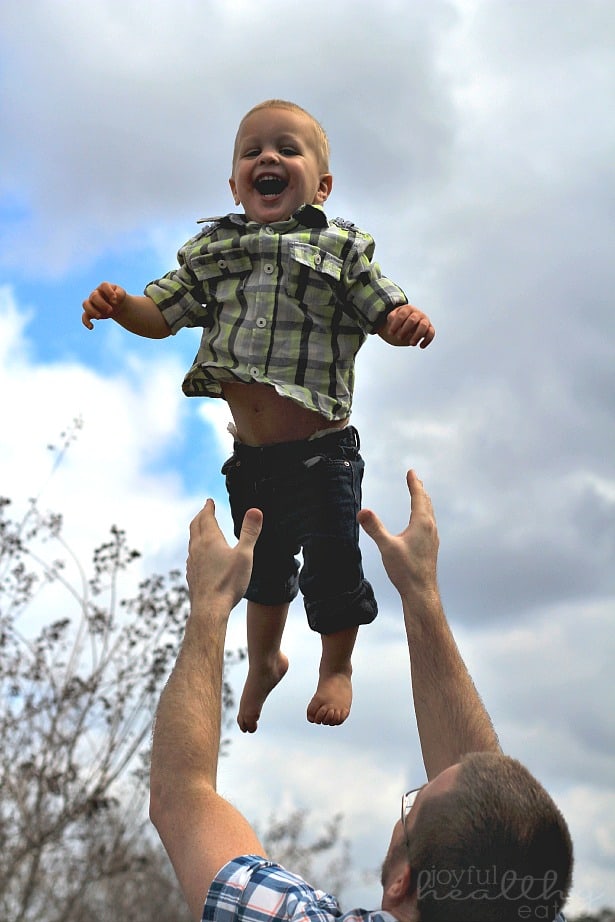 A toddler boy being tossed in the air by his dad