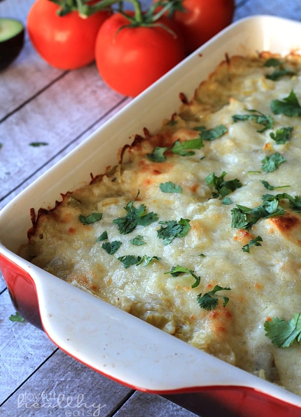 Chicken Enchilada Casserole in a baking dish topped with melted cheese and fresh herbs