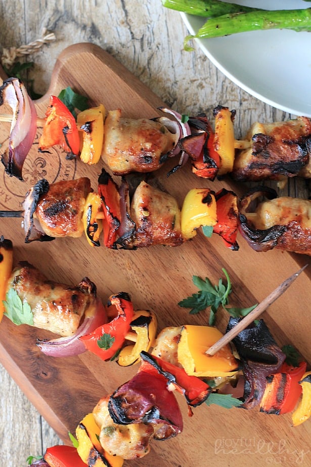 Top view of Grilled Chicken, Sausage, Pepper & Onion Kabobs on a Cutting Board