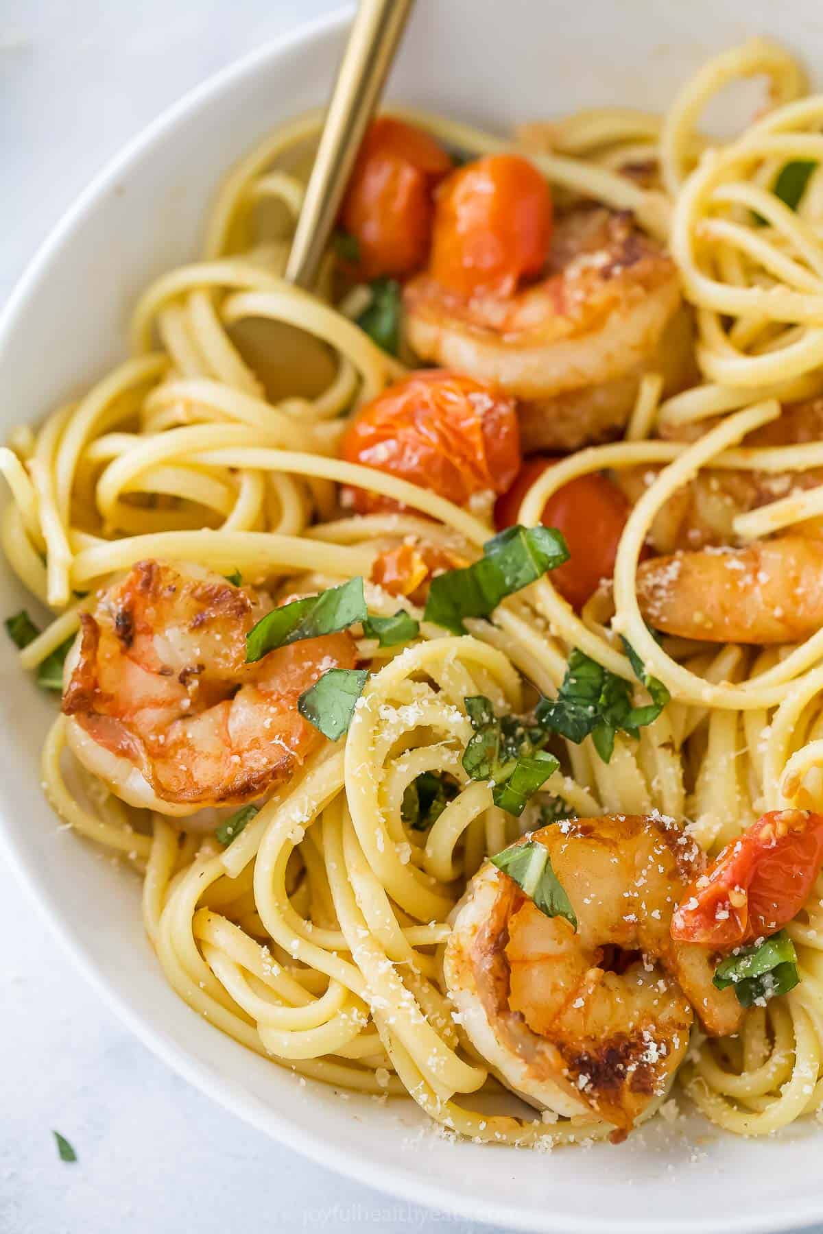This Spicy Shrimp Pasta is light and flavorful thanks to the addition of blistered cherry tomatoes and fresh basil. A 30-minute dinner! Closeup of spicy shrimp pasta with basil and blistered cherry tomatoes