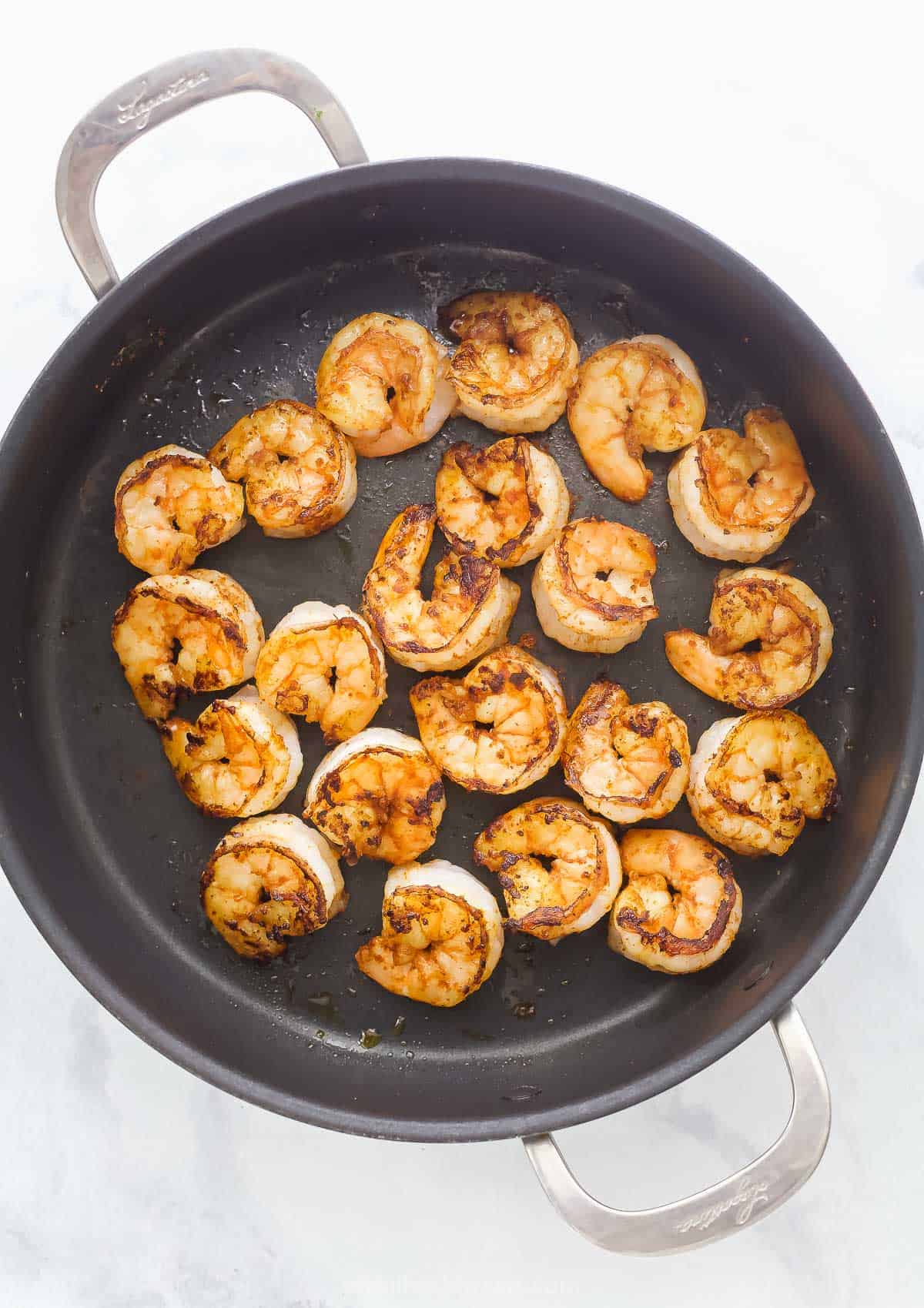 This Spicy Shrimp Pasta is light and flavorful thanks to the addition of blistered cherry tomatoes and fresh basil. A 30-minute dinner! Overhead view of shrimp cooking in skillet
