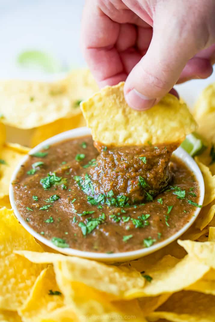 a hand with a chip scooping homemade restaurant style salsa