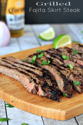 Grilled Fajita Skirt Steak sliced on a cutting board with fresh herbs and lime wedges