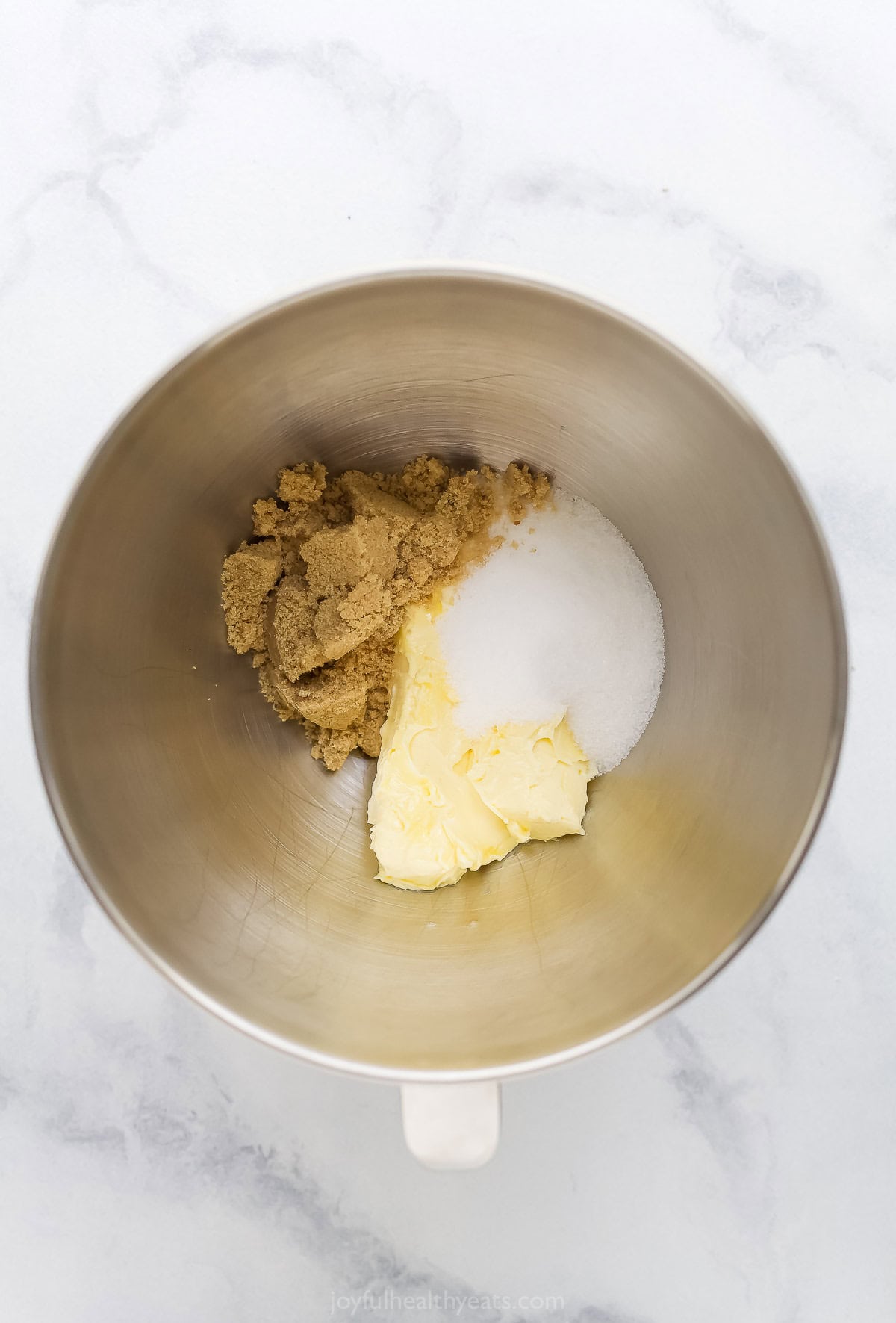Overhead view of white and brown sugar in mixing bowl with butter