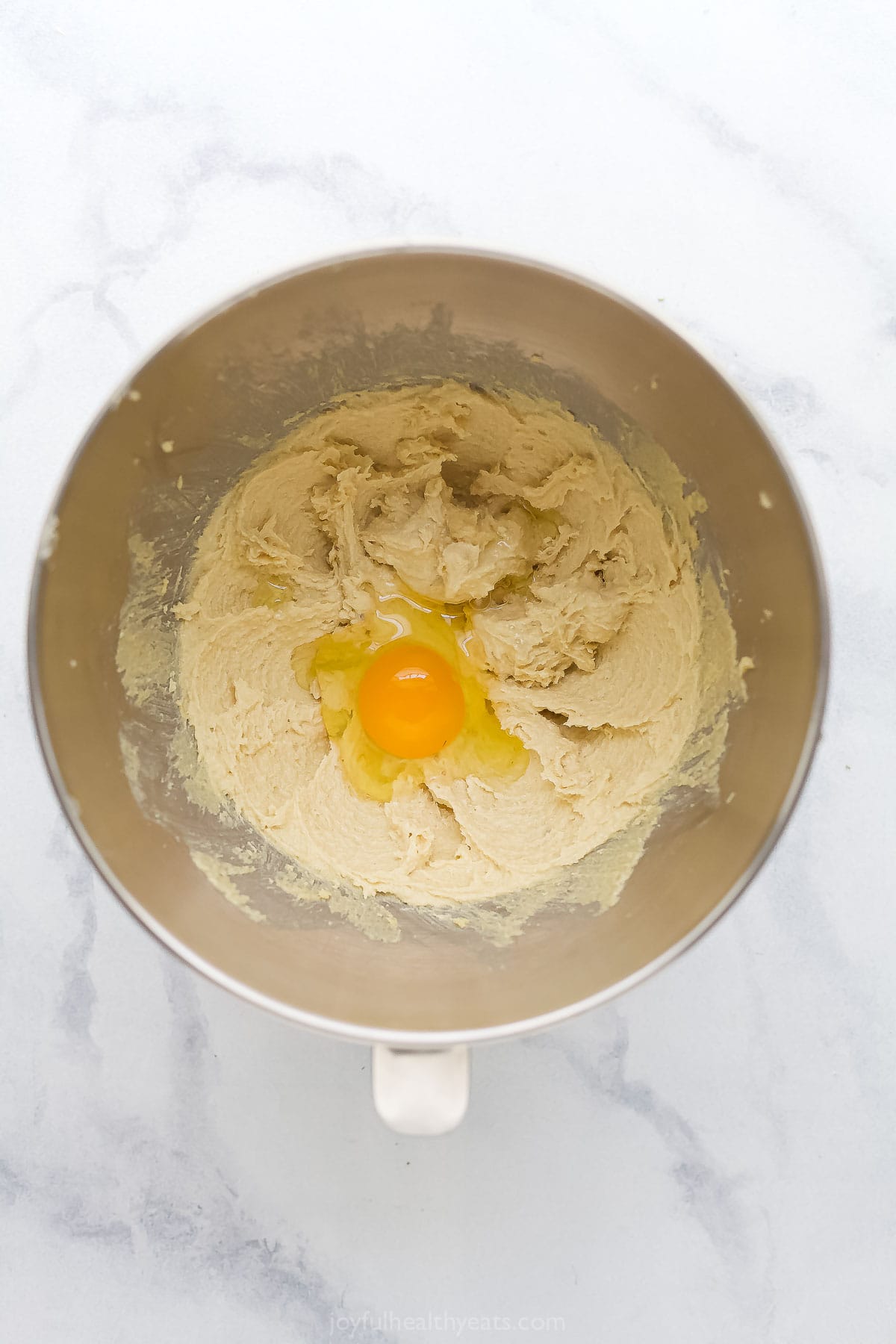 Overhead view of egg added to creamed butter and sugar