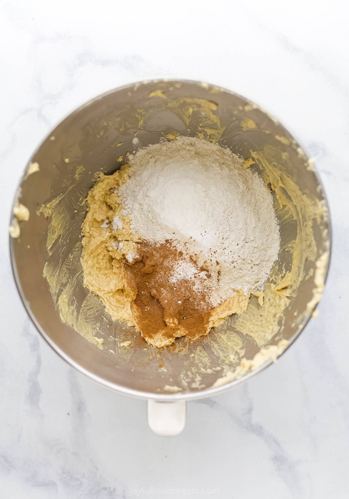 Overhead view of dry ingredients added to wet ingredients for soft chocolate chip cookie