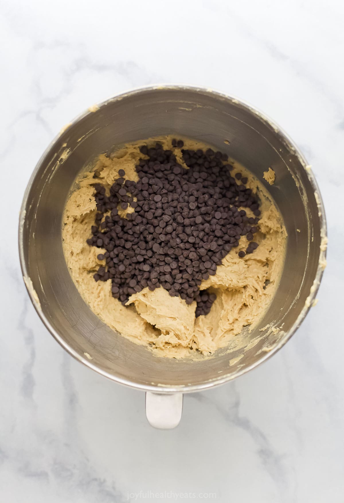 Chocolate chips added to bowl of cookie dough