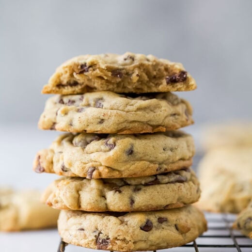 Stack of 5 soft chocolate chip cookies, with top cookie broken in half