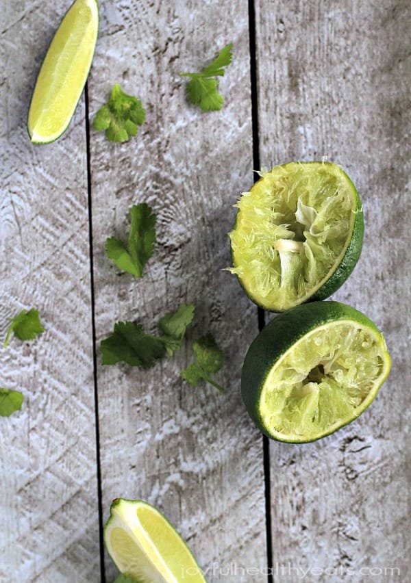 Two Squeezed Lime Halves on a Wooden Surface with Two Lime Wedges