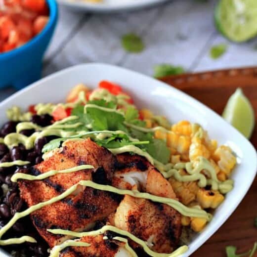 A Bowl of Grilled Tilapia and Veggies Next to Two Dishes Containing Corn and Tomatoes