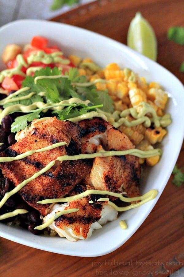 Grilled Tilapia in a White Bowl With Veggies and Avocado Crema Drizzle