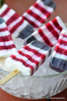 Red white and blueberry striped popsicles in a bowl of ice