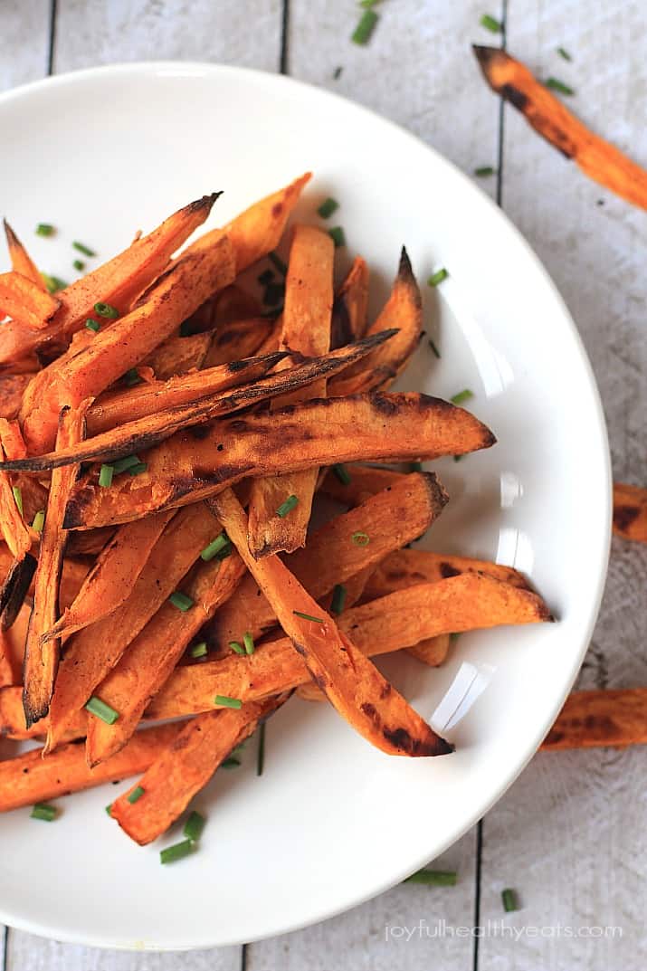 A close-up shot of crispy sweet potato fries piled onto a shiny white plate