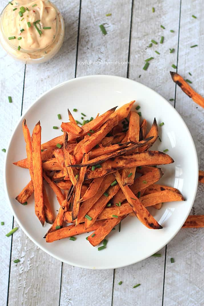 A plate containing sweet potato fries garnished with chopped fresh chives
