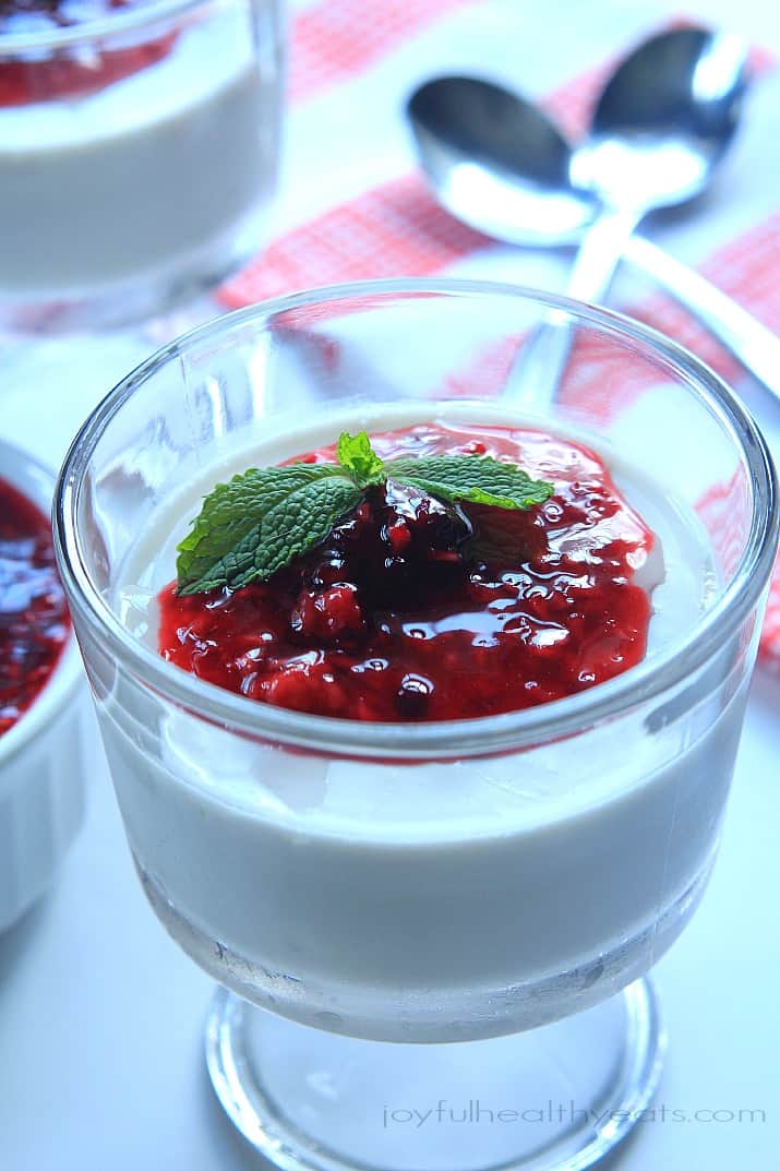 Coconut Panna Cotta topped with Raspberry Blackberry Compote in a dessert glass with fresh mint garnish