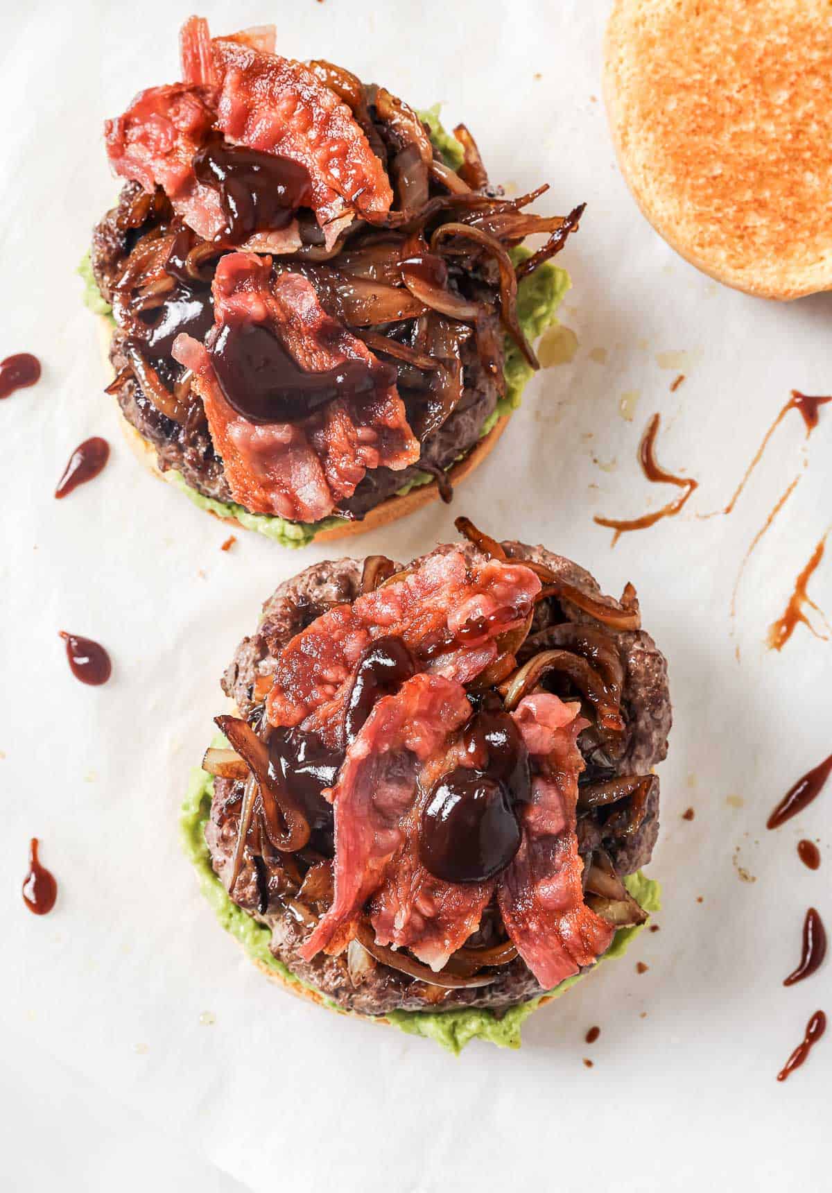 These Cowboy Hamburger Sliders are topped with creamy avocado, balsamic caramelized onions, and crispy bacon. Always a crowd-pleaser! Overhead view of cowboy hamburger sliders before adding top bun
