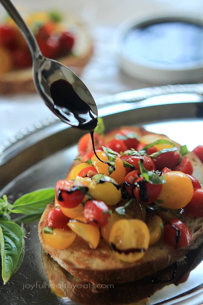 Balsamic drizzle being added to Fresh Tomato Bruschetta on a slice of toasted bread