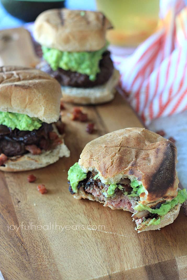 Gourmet "Cowboy" Slider burgers on a wooden board with a few bites out of one