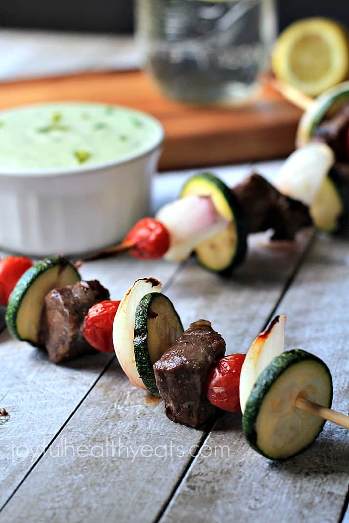 Close up view of Grilled Beef Kabobs with a bowl of Avocado Cucumber Tzatziki