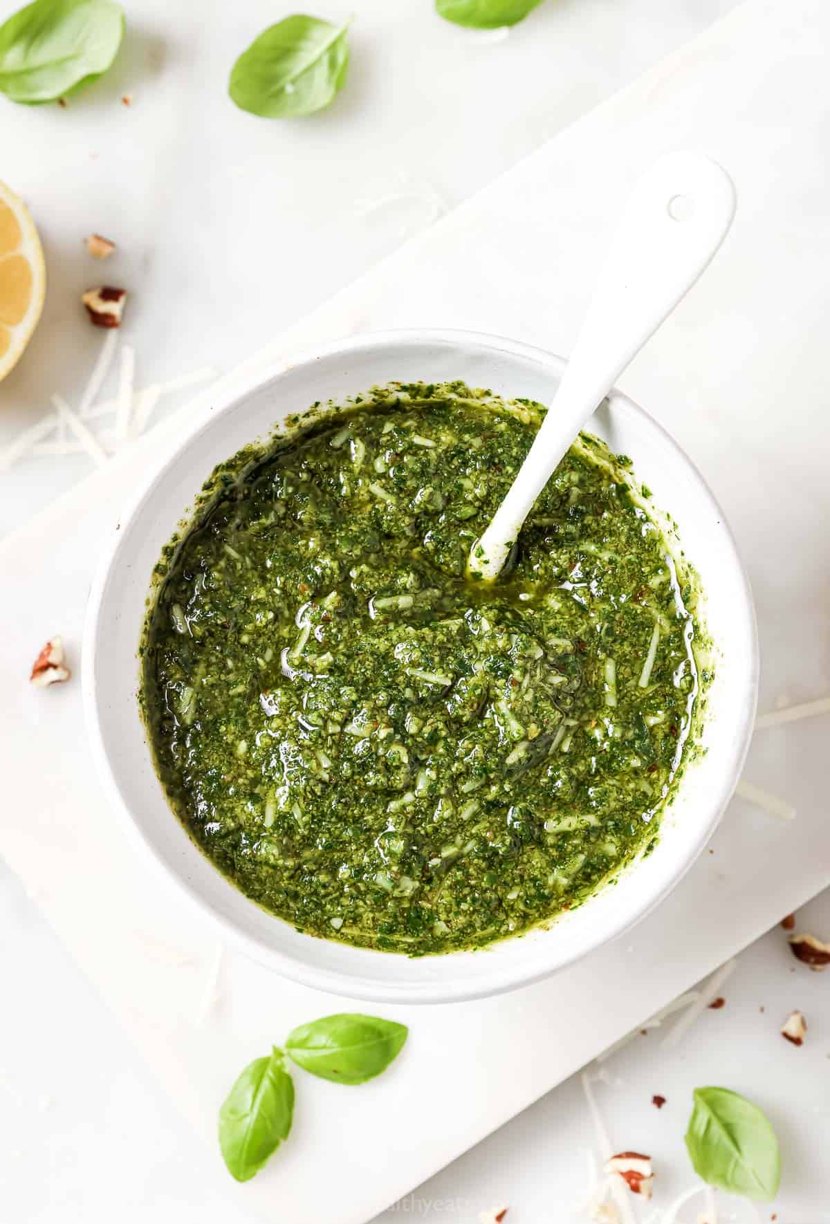 This Homemade Basil Pesto recipe is made with pecans instead of pine nuts to give it some extra body. It's my favorite way to make pesto! Overhead view of homemade basil pesto in bowl with spoon