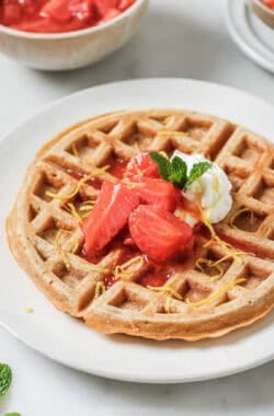 Crispy oatmeal waffle on plate with strawberry compote and whipped cream