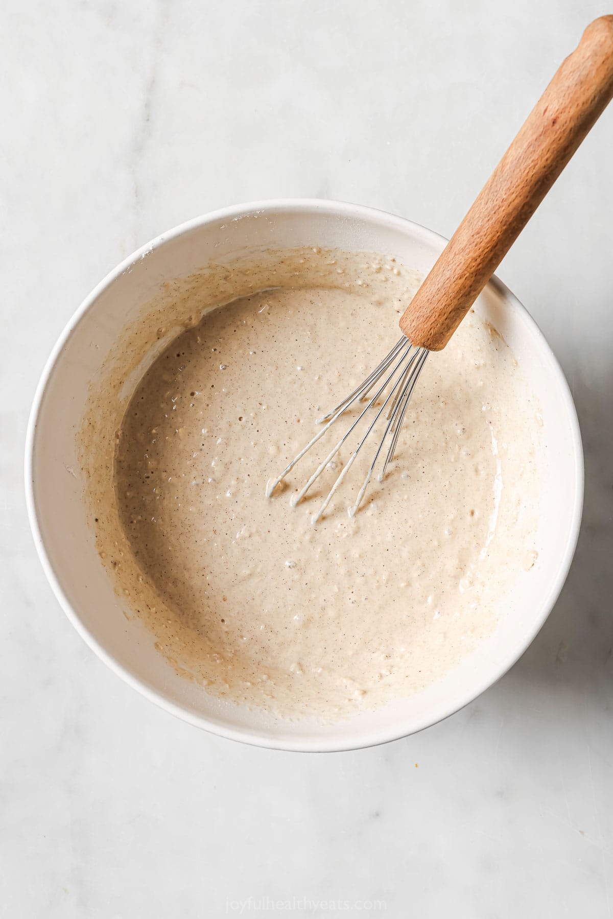 Overhead view of waffle batter in bowl with whisk