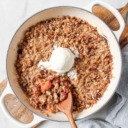Skillet of raspberry peach crisp with scoop of vanilla ice cream