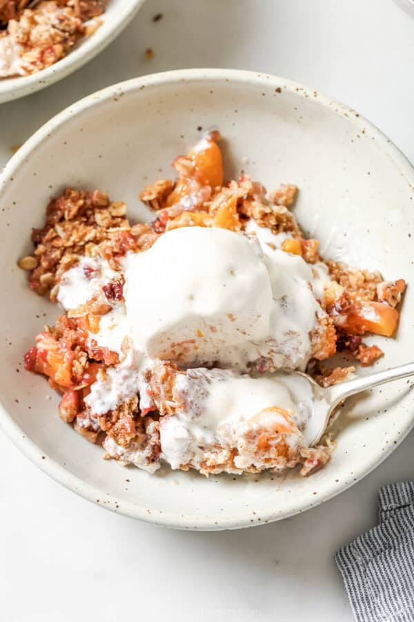 Raspberry peach crisp bowl with scoop of vanilla ice cream