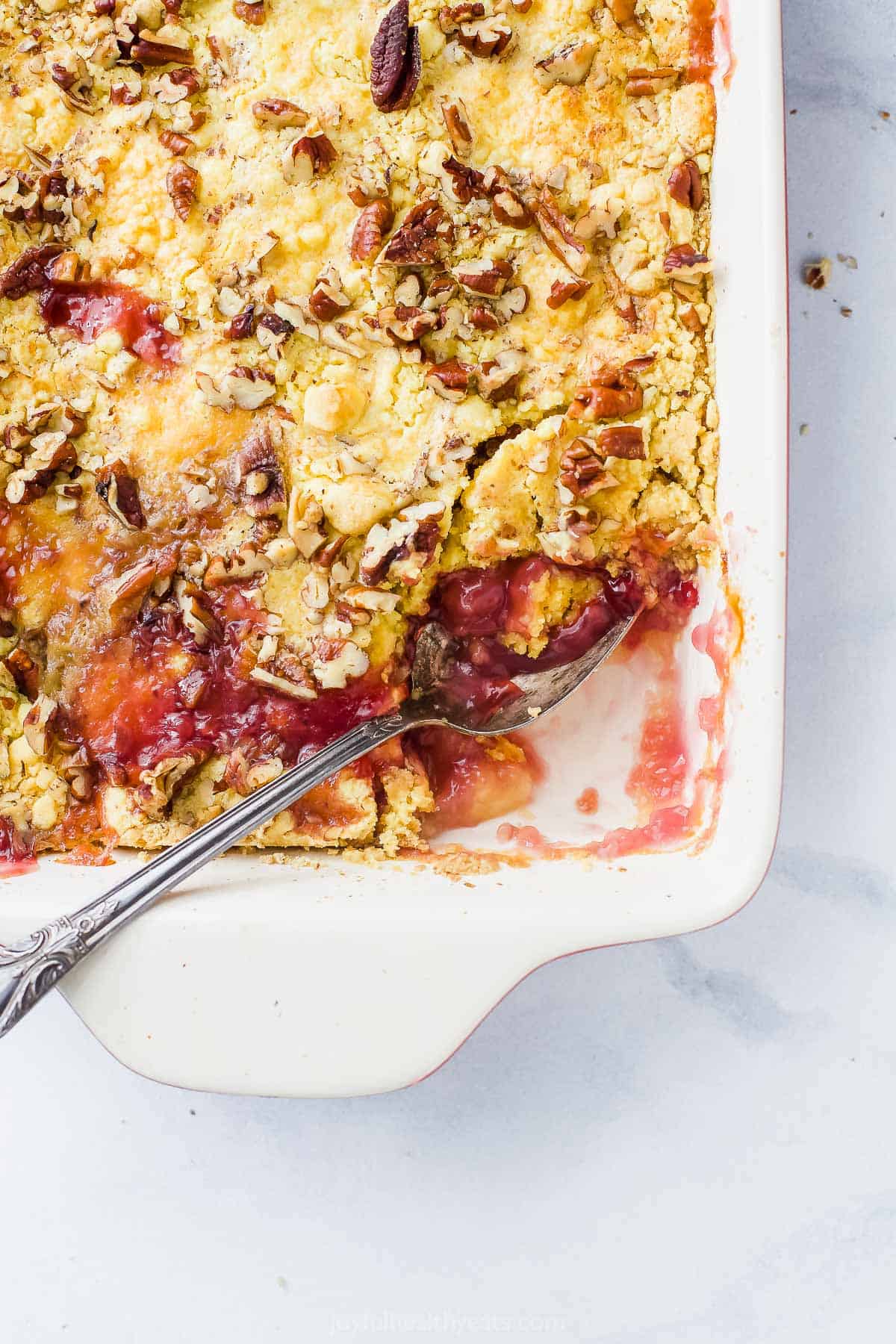 casserole dish with pineapple cherry dump cake with a scoop taken out