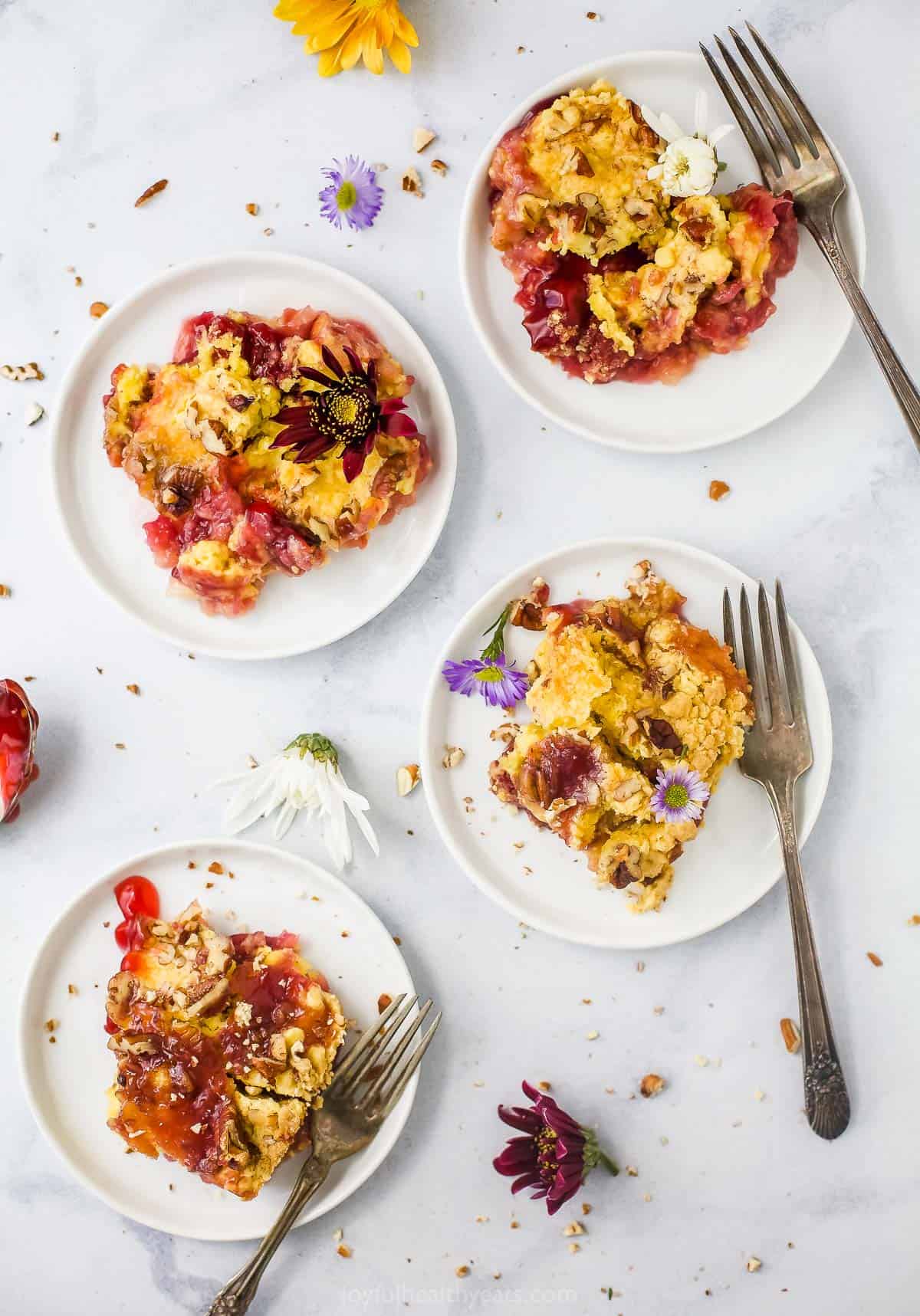 Four servings of Cherry Pineapple Dump Cake on plates with decorative wildflowers