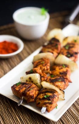 Two tomato and chicken kebabs on a plate