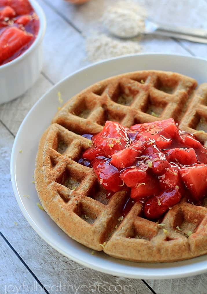 a waffle with berry compote on top on a white plate 