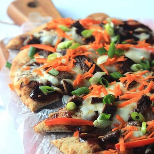 A Grilled Short Rib Flatbread on a Wooden Surface Covered in Wax Paper