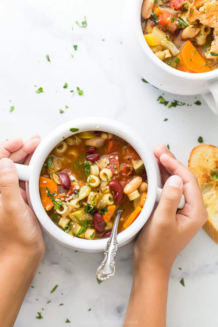 hands holding a crock filled with easy minestrone soup