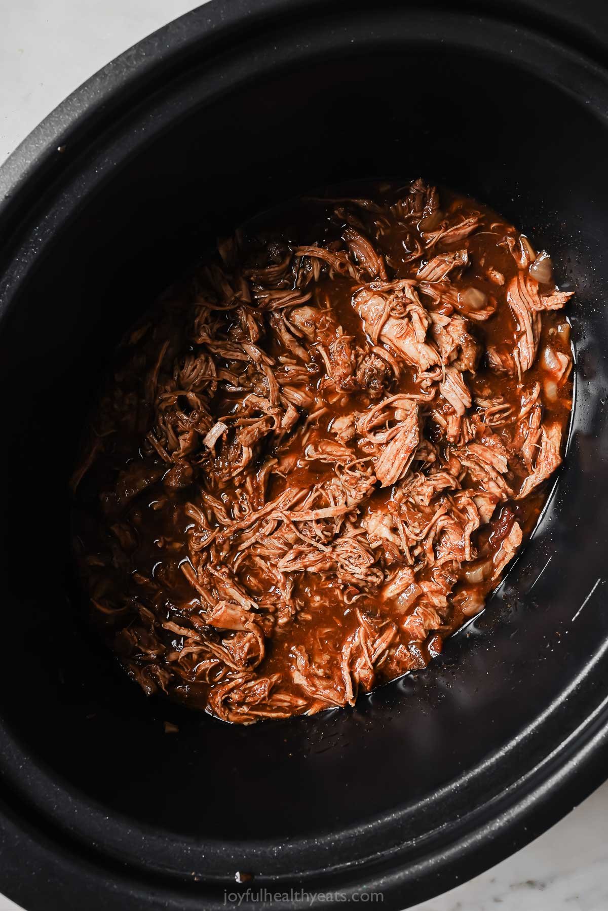 Returning the shredded pork to the sauce. 