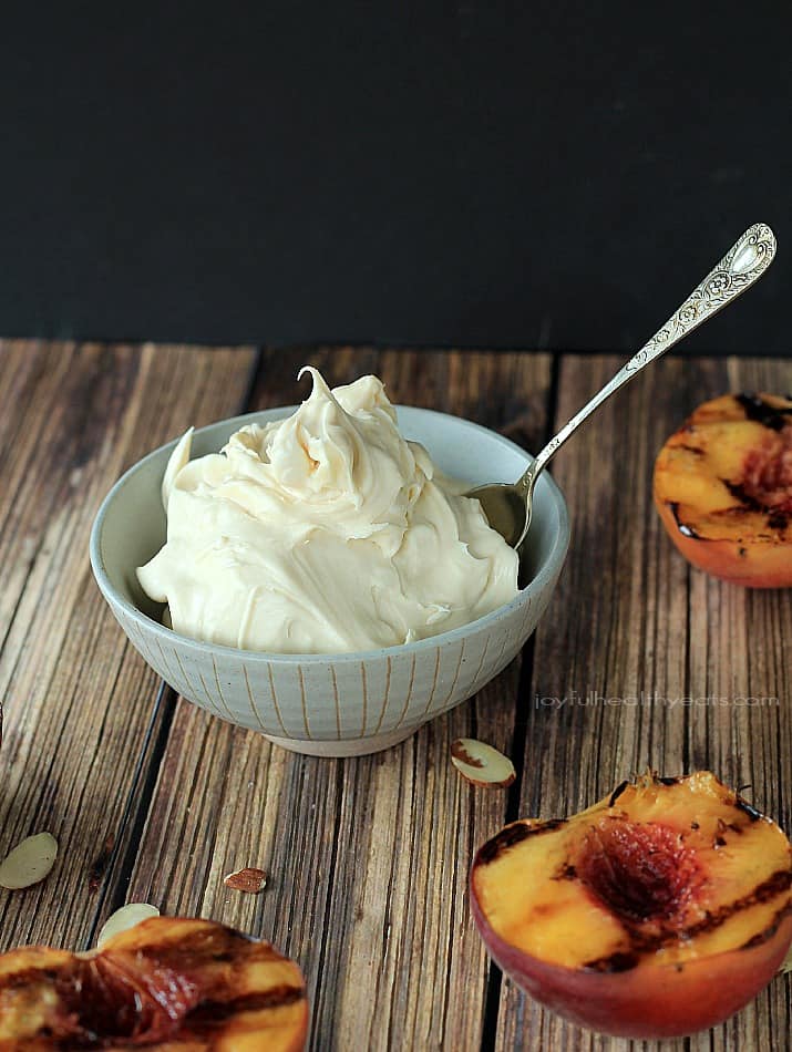 A bowl of Maple Honey Mascarpone Cheese next to grilled peaches on a wooden board