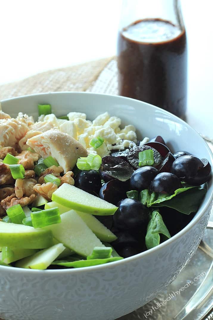 Chicken Feta Walnut Grape Chopped Salad in a bowl alongside a carafe of Balsamic Vinaigrette