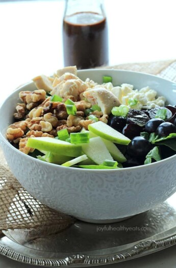 A Bowl of Chicken Feta Walnut Grape Salad Beside a Bottle of Honey Balsamic Vinaigrette