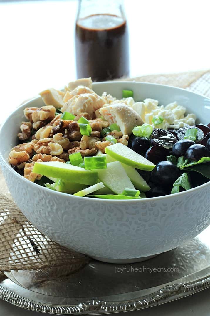 A Bowl of Chicken Feta Walnut Grape Salad Beside a Bottle of Honey Balsamic Vinaigrette