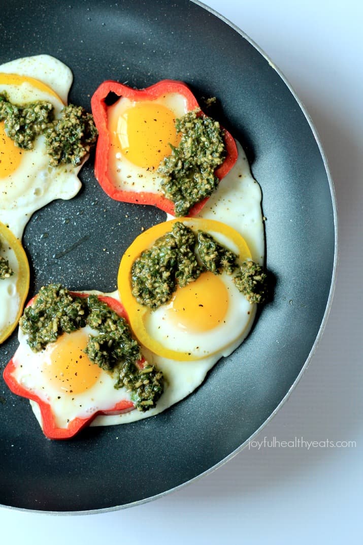 Top view of Egg in a Hole with Basil Pesto and bell pepper rings in a skillet