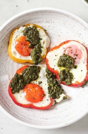 Eggs in a hole drizzled with pesto served on plate.