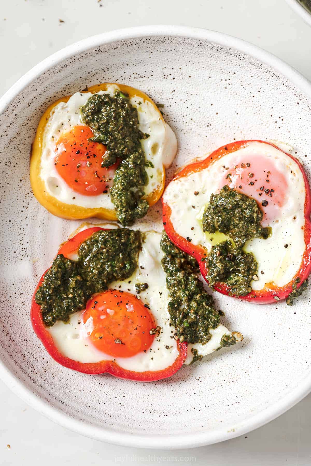 Eggs in a hole drizzled with pesto served on plate.